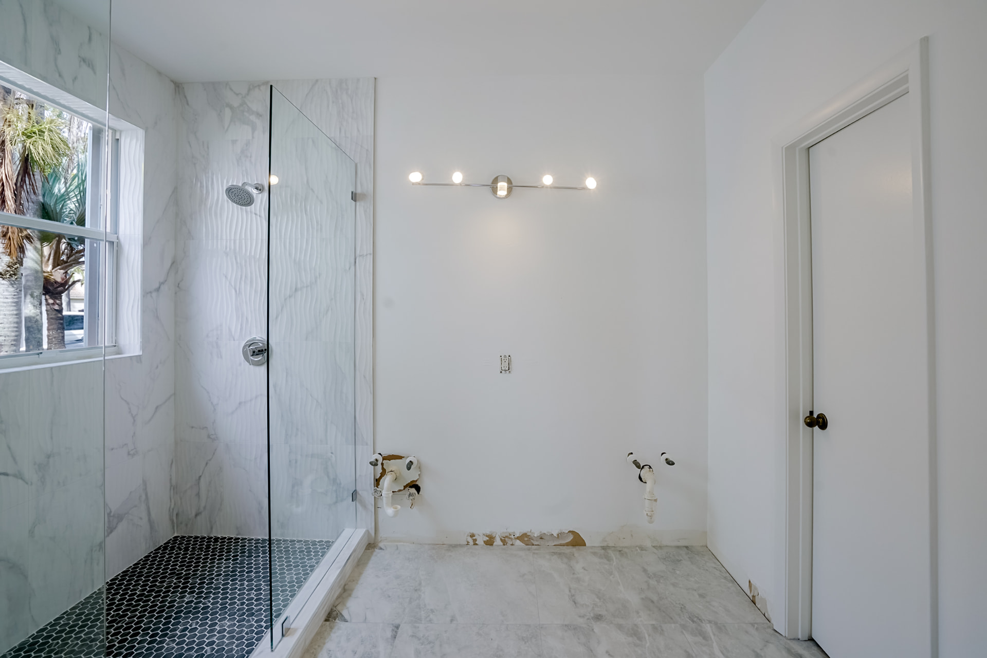 Before virtual staging: unfinished primary bathroom with exposed plumbing and no vanity